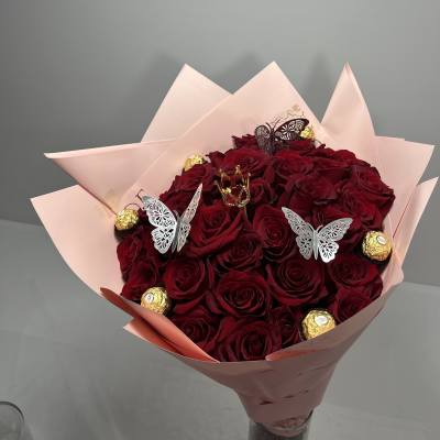 Bouquet of red roses wrapped in pale pink paper with gold chocolates and butterfly picks