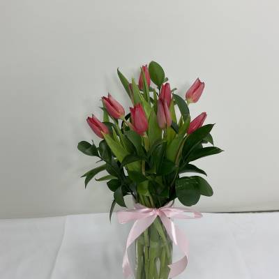Pink tulips in a clear glass vase tied with a pink ribbon