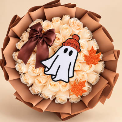 Bouquet of cream roses with a ghost decoration and autumn leaves
