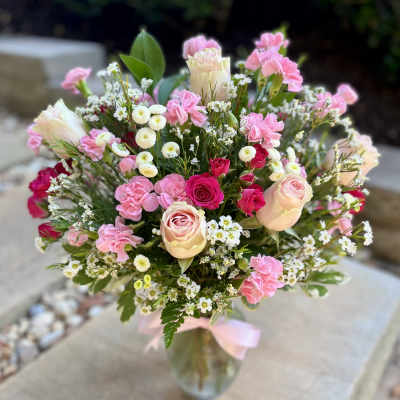 Pink and cream bouquet with roses and carnations in a glass vase