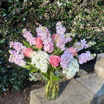 Pink roses and lavender flowers arranged in a clear glass vase