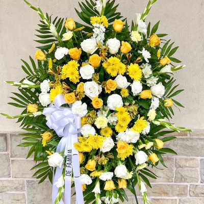 Large yellow and white funeral wreath with ribbon on an easel