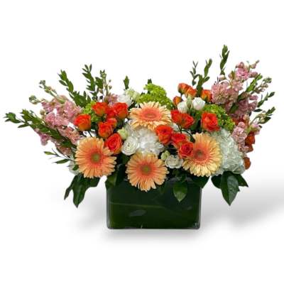 Mixed bouquet in a square glass vase with peach gerberas and orange roses