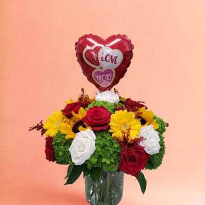 Bouquet of red, white, and yellow flowers with a heart-shaped love balloon in a glass vase