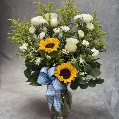 Sunflower and white rose bouquet in a glass vase with a blue ribbon