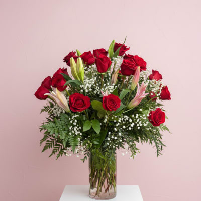 Red roses and lilies arranged in a clear glass vase