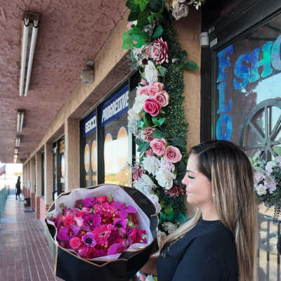 Woman holding a large bouquet of pink flowers wrapped in black paper