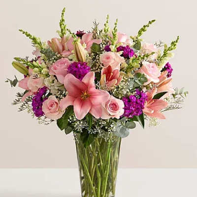 Pink lilies and roses arranged in a clear glass vase