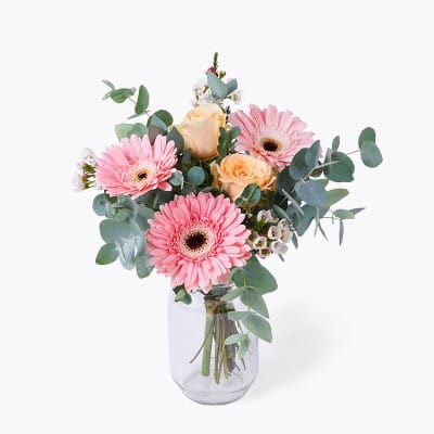 Pink gerbera daisies and peach roses in a glass vase