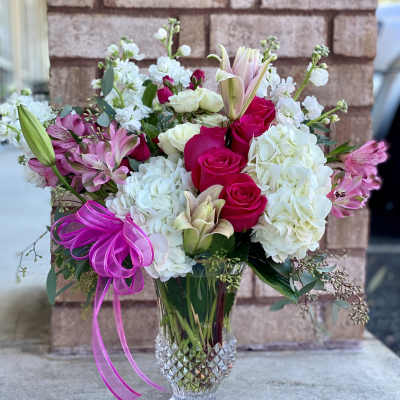 Bouquet of pink roses, white hydrangeas, and lilies in a clear glass vase