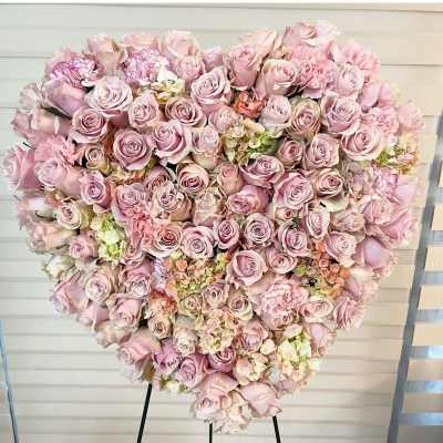 Heart-shaped arrangement of pale pink roses and carnations on an easel