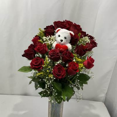 Red rose bouquet with a small teddy bear in a glass vase