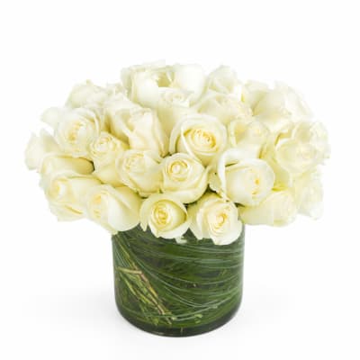 White roses arranged in a clear glass vase with green stems visible