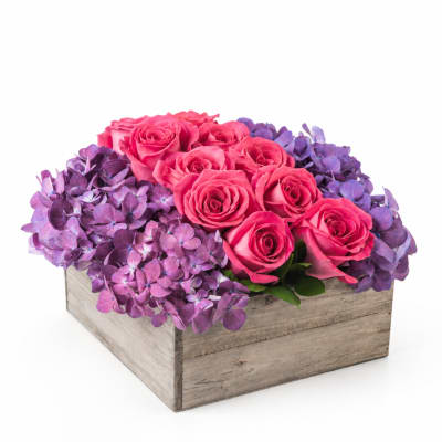 Pink roses arranged with purple hydrangeas in a wooden box