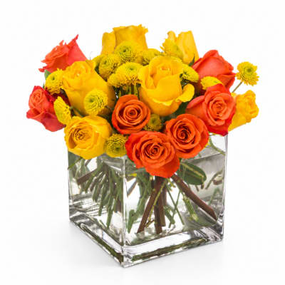 Yellow and orange roses with small yellow blooms in a clear square vase