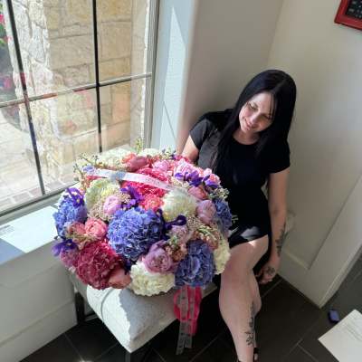 Large bouquet of pink, purple, and white flowers held by a seated woman