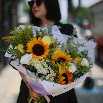 Bouquet with sunflowers, white blooms, and eucalyptus in pastel wrap