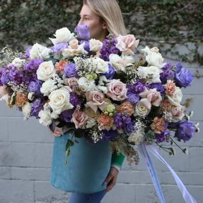 Large bouquet of purple, white, and blush roses held by a woman