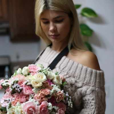 Woman holding a large bouquet of pink and cream roses