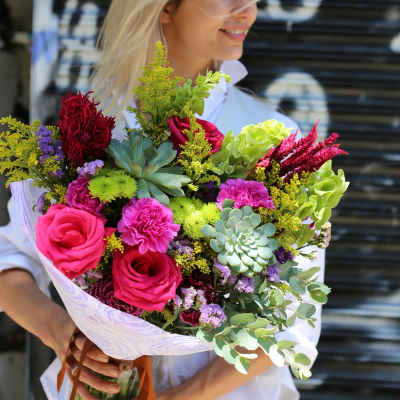 Bouquet of pink roses, succulents, and mixed flowers wrapped in white paper