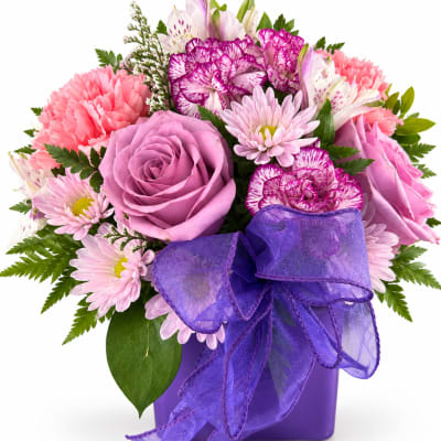 Pink and purple bouquet in a purple vase with a large ribbon