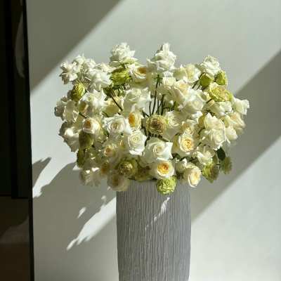 White roses arranged in a tall textured vase