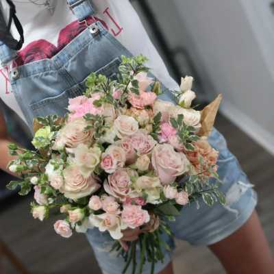 Handheld bouquet of pale pink and white roses with greenery