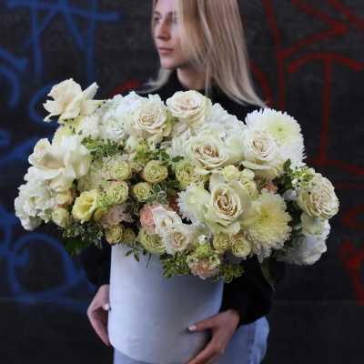 Woman holding a large white floral arrangement in a round box