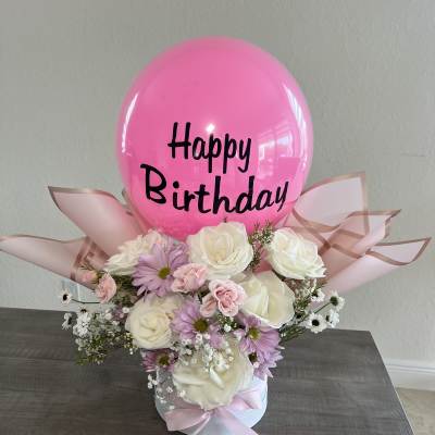 Pink birthday balloon above a pastel flower arrangement in a white box