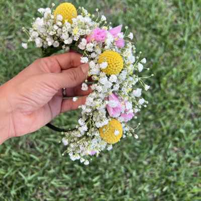 Handheld flower crown with white baby's breath, yellow blooms, and pink flowers