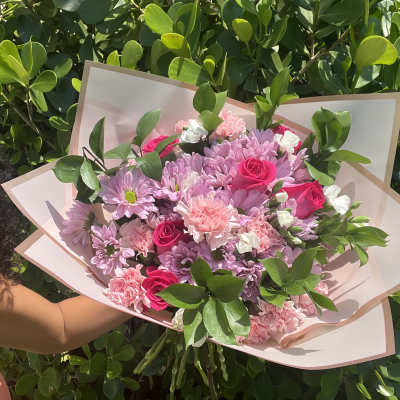 Pink and lavender bouquet with roses and daisies in pale wrapping