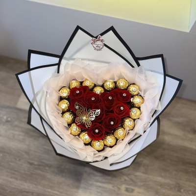 Heart-shaped bouquet of red roses and gold chocolates wrapped in white paper