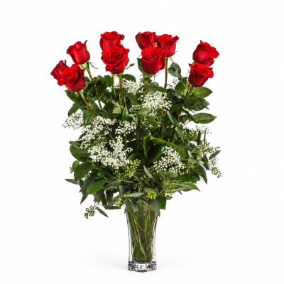 Red roses arranged in a clear glass vase with white filler flowers