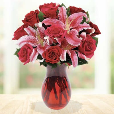 Red roses and pink lilies in a red glass vase
