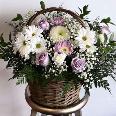 Basket arrangement of lavender roses, white daisies, and pink mums
