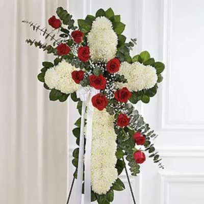 Cross-shaped floral arrangement with red roses and white chrysanthemums on a stand