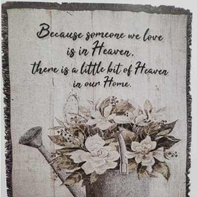 Decorative sign with a watering can and white flowers, plus a memorial quote