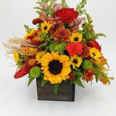 Autumn floral arrangement with sunflowers and mums in a dark wooden box