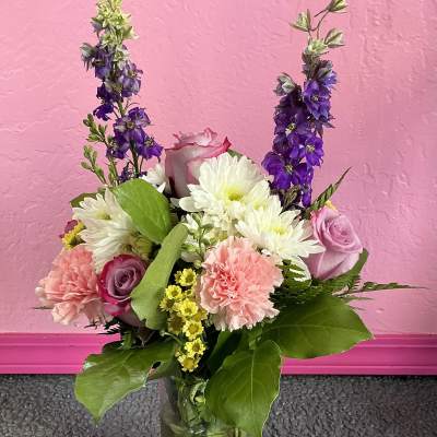 Mixed bouquet of pink, white, and purple flowers in a glass vase