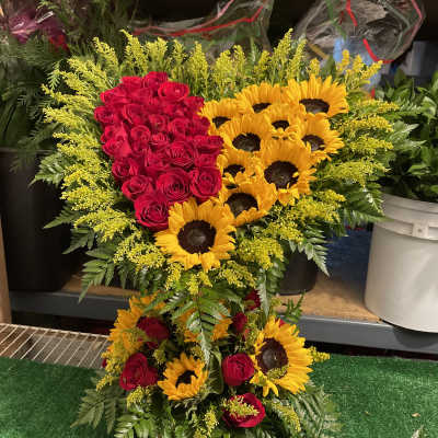 Heart-shaped arrangement of red roses and yellow sunflowers