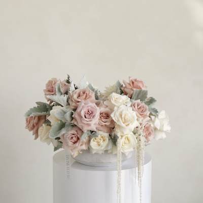 Blush and white roses arranged in a low round box.