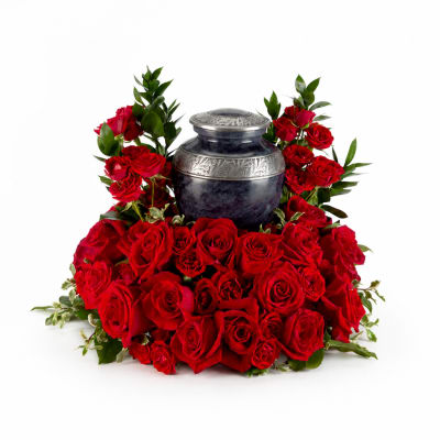 Red roses arranged around a dark urn with silver accents