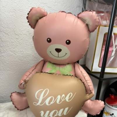 Pink teddy bear balloon holding a heart balloon that says "Love you"