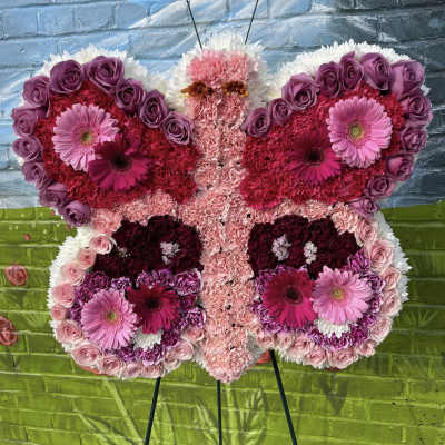 Butterfly-shaped floral arrangement in pink, purple, and white on an easel