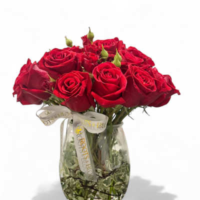 Red roses arranged in a clear glass vase with a ribbon bow