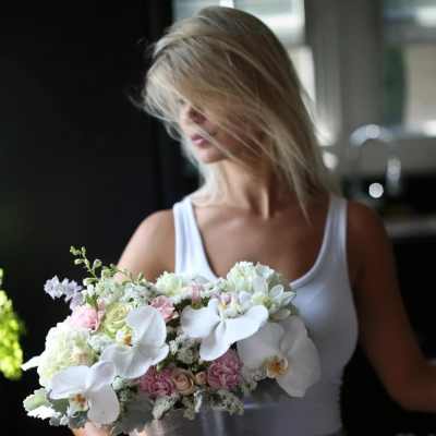 Woman holding a pastel bouquet with white orchids and pink flowers