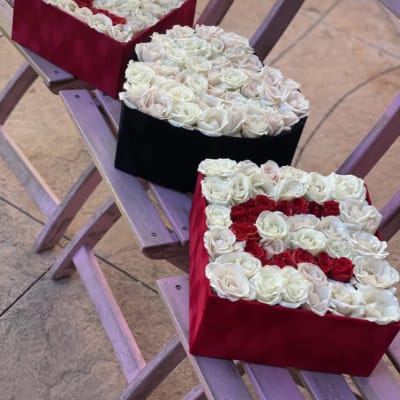 Three heart-shaped rose boxes in red, black, and red
