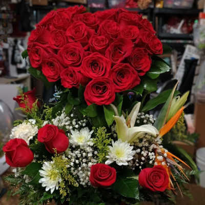 Large bouquet of red roses with white flowers in a wooden container