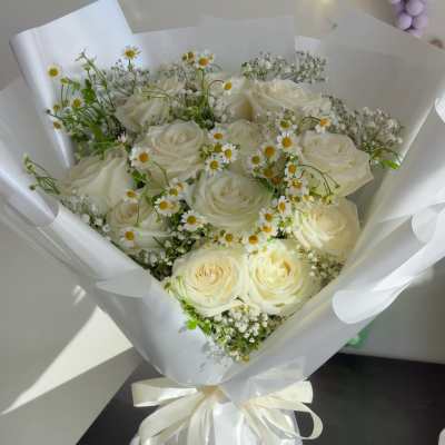 Bouquet of white roses and small daisy flowers wrapped in white paper