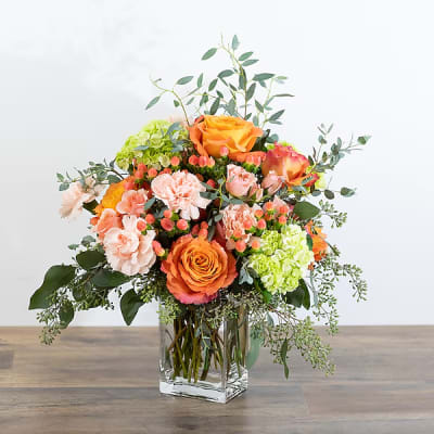 Orange and peach bouquet in a clear glass vase